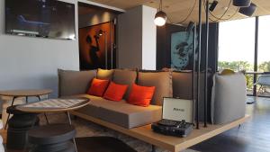 sala de estar con sofá con almohadas de color naranja y mesa en ibis Melun, en Melun