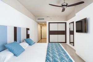 a bedroom with two beds and a flat screen tv at Hotel Riu Costa del Sol - All Inclusive in Torremolinos