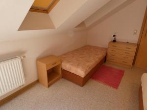 a small bedroom with a bed and a dresser at Pension Ufert in Meißen