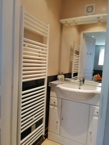 uma casa de banho branca com um lavatório e um espelho em Charmant studio á Autrans em Autrans