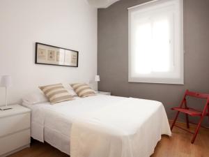 una camera con un letto bianco e una sedia rossa di Sagrada Familia a Barcellona