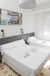 two beds in a white room with a picture on the wall at NWT Central Station Valencia in Valencia