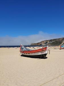 a boat sitting on the sand on a beach at A Casa dos Avós in Nazaré