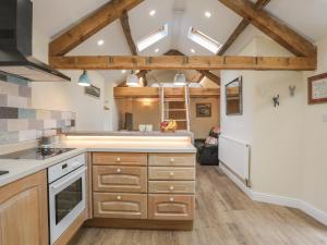 Il comprend une cuisine avec des placards en bois et un plafond avec des lucarnes. dans l'établissement Glan Meon Cottage, à Barmouth