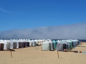 a row of tents and chairs on a beach at A Casa dos Avós in Nazaré