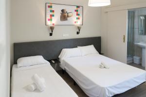 two beds in a room with white sheets at NWT Central Station Valencia in Valencia