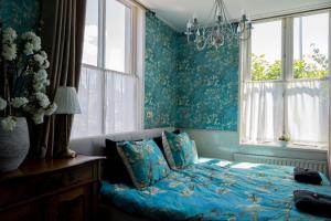 um quarto com uma cama com paredes azuis e um lustre em B&B 't Raethuys em Dirkshorn