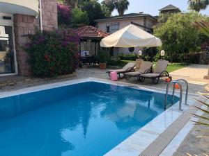 a swimming pool with a umbrella and chairs and a house at Dreamhome in Alanya