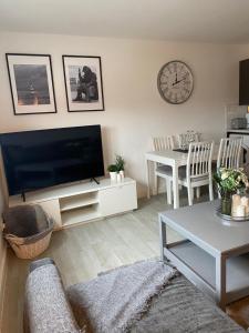 a living room with a flat screen tv and a table at Coalhouse Apartment in Seaham