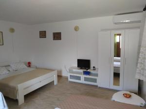 a white bedroom with a bed and a television at Anita studio 3 Apartment in Mali Lošinj