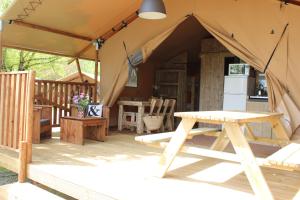 a tent with a picnic table on a deck at Glamping Lac du Causse in Lissac-sur-Couze