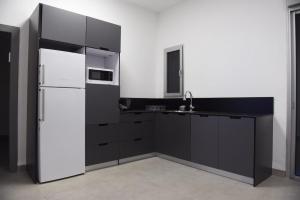 uma cozinha com armários pretos e um frigorífico branco em בית דירות - בית אורן em Bet Sheʼan