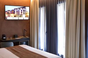 a hotel room with a bed and a desk and a window at Hotel Bell'arrivo by Dori in Peschiera del Garda