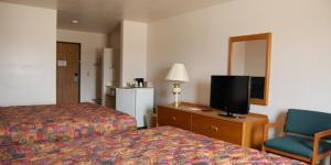 una camera d'albergo con letto, TV e sedia di Country Haven Inn a Hillsboro