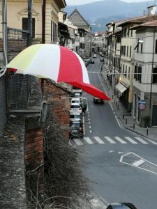 un paraguas rojo y blanco en el lateral de un edificio en Alle vecchie mura, en Pistoia