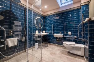 a blue tiled bathroom with a toilet and a sink at The Three Blackbirds in Stetchworth