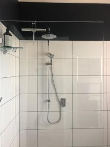 um chuveiro na casa de banho com azulejos brancos em Salt 112 House em Albany