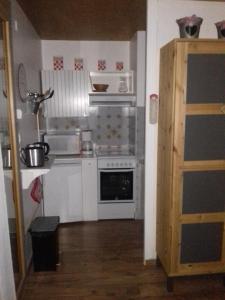 una pequeña cocina con electrodomésticos blancos y suelo de madera. en 2 Alpes-locations Studio 4 personnes, en Les Deux Alpes