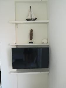 einen Flachbild-TV an einer Wand mit Regalen in der Unterkunft Home 4you in Karlovasi