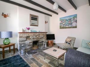 ein Wohnzimmer mit einem Kamin und einem Sofa in der Unterkunft Nasturtium Cottage in Par