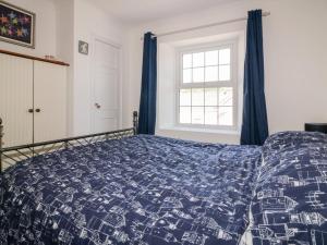 - une chambre avec un lit doté d'une couette bleue et d'une fenêtre dans l'établissement Nasturtium Cottage, à Par