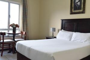 a bedroom with a bed and a table and a window at Regal Inn PMBurg in Pietermaritzburg