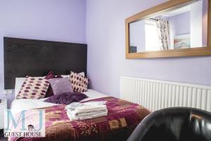 a bedroom with a bed with a mirror on the wall at M and J Guest House in Cleethorpes