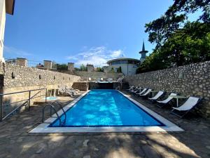 une piscine avec des chaises et une montagne en arrière-plan dans l'établissement Bástya Konferencia és Wellness Hotel, à Miskolctapolca