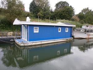 une maison bleue sur un bateau dans l'eau dans l'établissement Sportboot Zander, à Bornheim