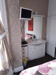 a bathroom with a sink and a tv on the wall at The Driftwood Hotel in Blackpool