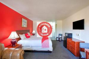 a hotel room with a bed with a red wall at Capital O Padre Island Corpus Christi in Corpus Christi