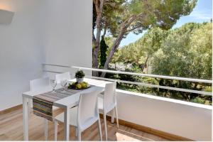 uma mesa de jantar branca com cadeiras brancas e uma grande janela em Apartamento Ferrera Park 615 em Cala Ferrera