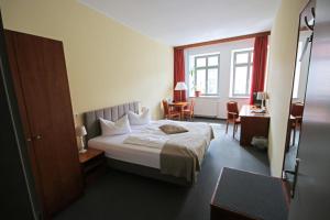 a hotel room with a bed and a desk at Hotel Zittauer Hof in Zittau