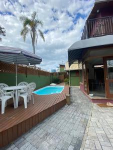 a patio with a table and chairs and a pool at Vila Figueiredo das Donas in Bombinhas