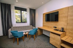 a hotel room with a couch and a table and chairs at Hotel Salis in Tuzla