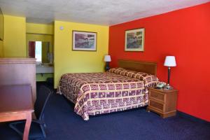 a hotel room with a bed and red and yellow walls at Homeplace Inn in Jacksonville