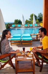 um grupo de pessoas sentadas numa mesa perto de uma piscina em Alacati VillaRenk em Alacati