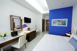 1 dormitorio con pared azul, escritorio y cama en Hotel Mykonos en Santiago de Veraguas