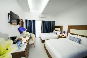Una habitación de hotel con dos camas y un escritorio con televisión. en Hotel Mykonos, en Santiago de Veraguas 33 fotos más