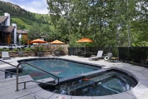 a swimming pool with chairs and umbrellas on a patio at Durant 6D in Aspen