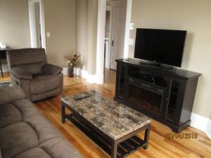 a living room with a flat screen tv and a coffee table at Executive Suites Bathurst in Bathurst