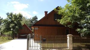 una casa con una valla de madera delante de ella en Godzisz - domek rekreacyjny en Sobolew