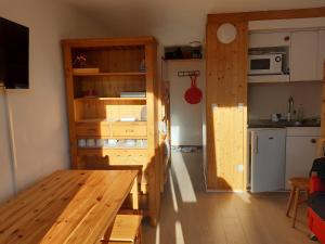 a room with a wooden table and a kitchen at Ski Soleil 304 in Manigod