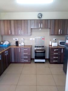 a kitchen with wooden cabinets and a stove at Shanzu Beach apartment with stunning Ocean view in Mwakirunge