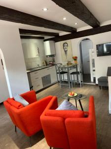 a living room with orange chairs and a kitchen at Ackerbürgerhaus von 1604 in Goslar