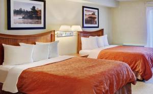 a hotel room with two beds with orange sheets at Thompson's Best Value Inn & Suites in Thompson
