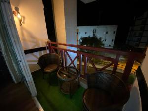 a balcony with three chairs and a table and a railing at EagleNest at Iris House Resort in Tanah Rata