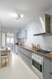 a large kitchen with white appliances and a table at Avenida Apartment by MP in Vila Nova de Gaia