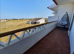 einen Balkon mit einem Stuhl und Blick auf ein Feld in der Unterkunft Trail House- Countryside and Beach in Longueira