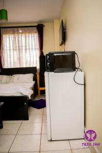 Zimmer mit einem Kühlschrank und einem TV darüber. in der Unterkunft The Trio Inn in Nairobi